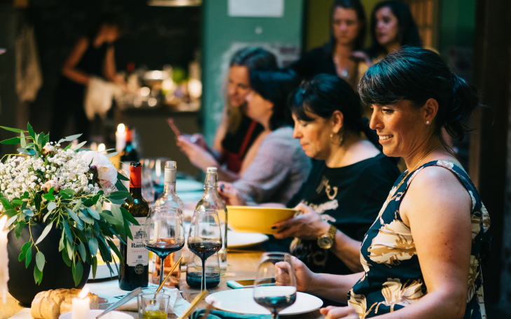 Gedeckter Tisch mit Personen die Netzwerken. Zum Soul Dinner steht eine bunte Auswahl an Essen und Getränken sowie Gesprächsanregungen bereit